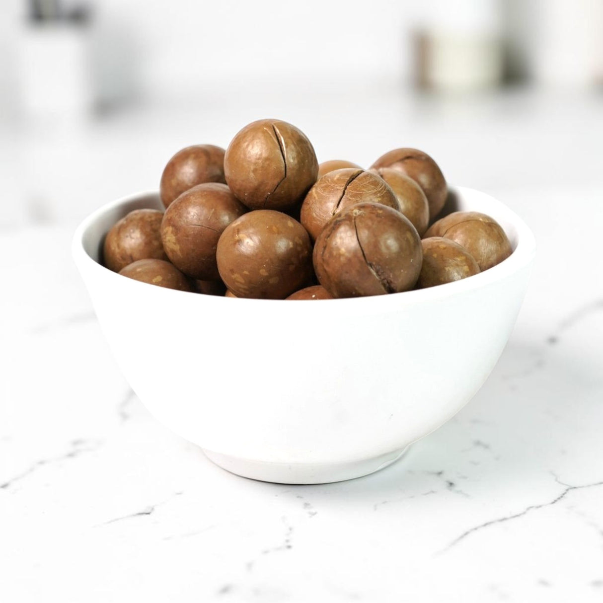 Mahnaz Food premium macadamia nuts with hard shells served in a white bowl