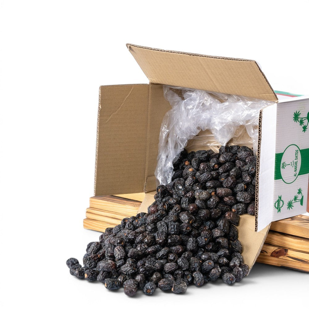Mahnaz Food premium Ajwa dates spilling from a cardboard box, dark brown, soft texture, naturally dried, rich in nutrients.