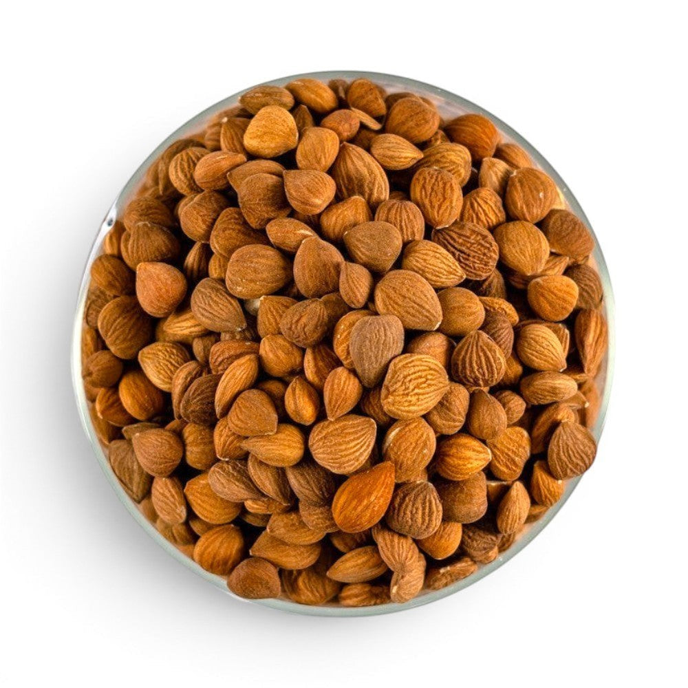 Mahnaz Food bitter apricot kernels in a glass bowl, showing natural brown seeds from inside the apricot stone.