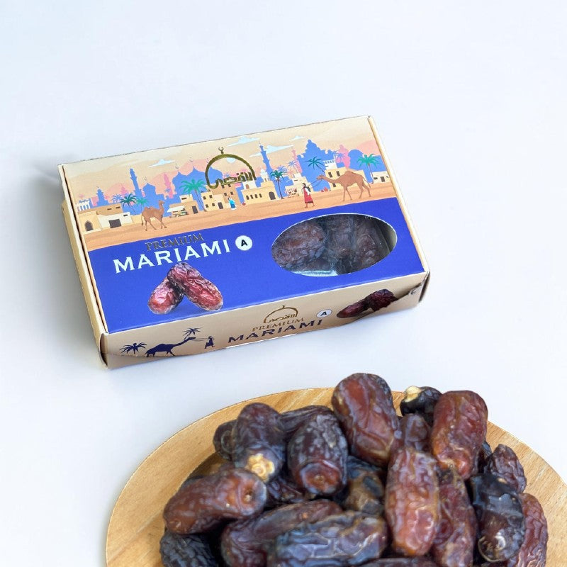 Mahnaz Food Mariami Dates, premium jumbo size, golden to dark brown with chewy texture, in a box with desert scene.