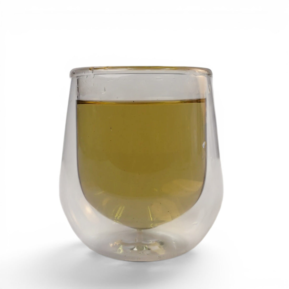 Mahnaz Food Nettle Tea, loose leaf herbal infusion in a clear double-walled glass. Golden yellow liquid.