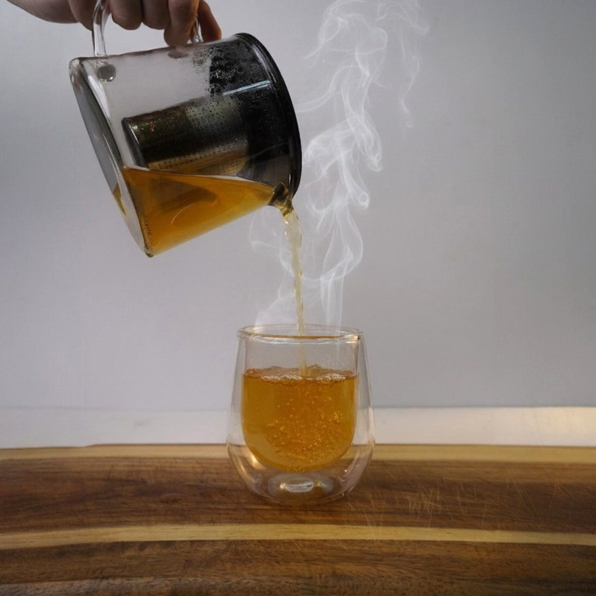 Mahnaz Food Royal Green Tea being poured into a double-walled glass cup. Made from senna leaves, caffeine-free.