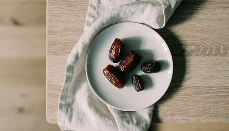 A small white plate with a modest portion of Medjool and Ajwa dates