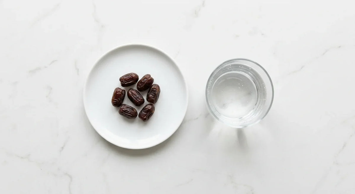 A small white plate holding a modest portion of dates in bright natural light