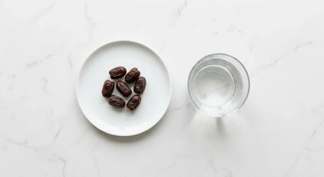 A small white plate holding a modest portion of dates in bright natural light