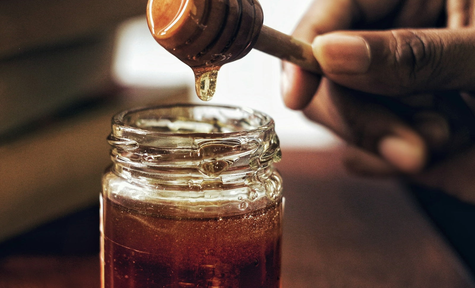 Tangan memegang gayung madu yang penuh dengan madu, kaya dengan khasiat madu lebah.