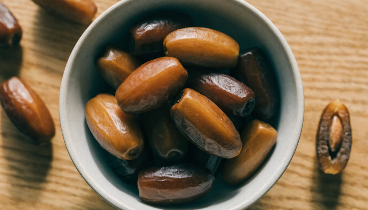 Bowl of golden to dark brown elongated Mariami dates, one sliced open