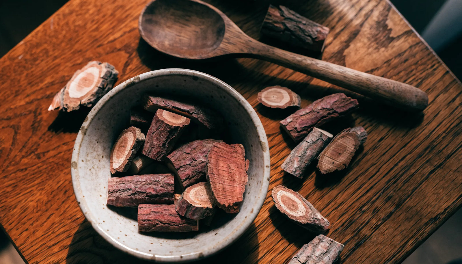 Bowl of dried reddish-brown red sage root slices on a dark wooden table