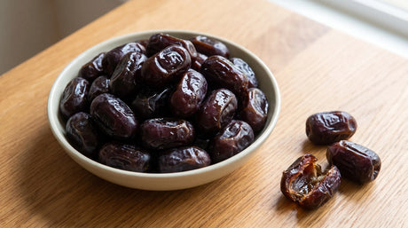 Bowl of dark glossy fresh Rotab dates, soft and visibly moist