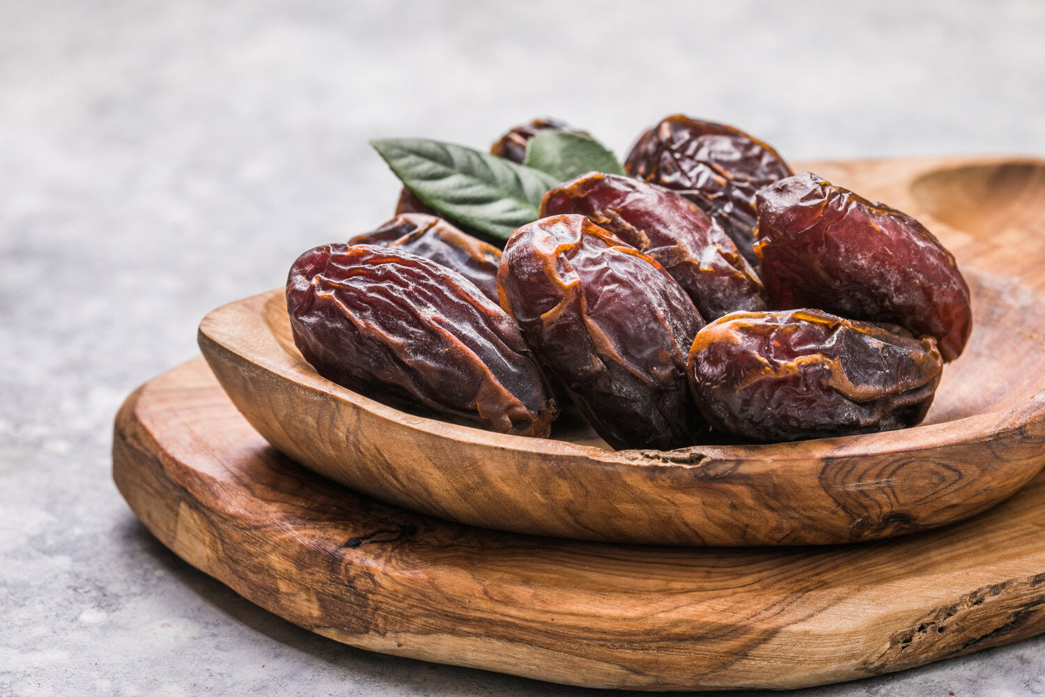 Kurma besar di atas pinggan kayu, salah satu makanan sunnah yang kaya dengan khasiat.