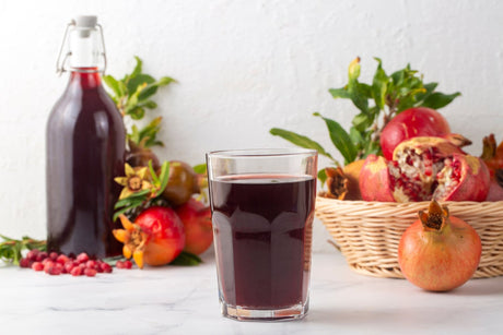 Segelas pati delima dengan beberapa buah delima di sebelah.