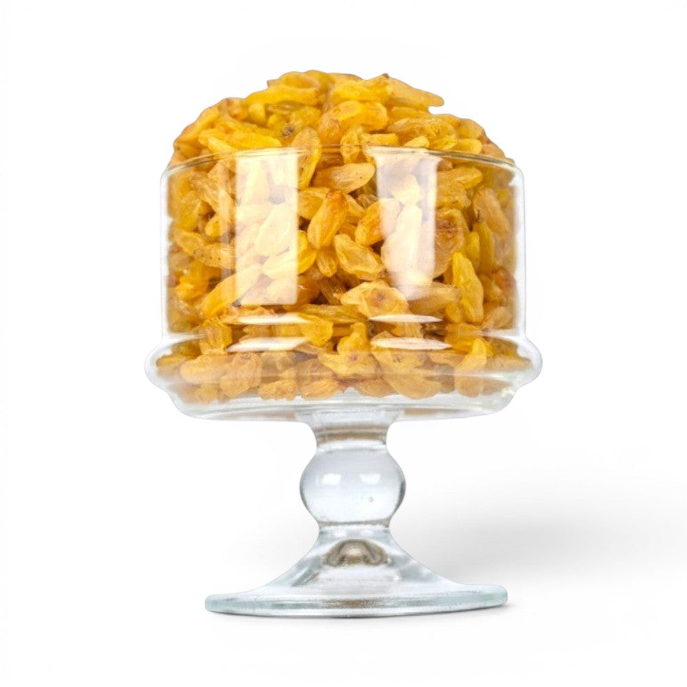 Mahnaz Food long golden raisins piled in a clear glass pedestal bowl against a white background