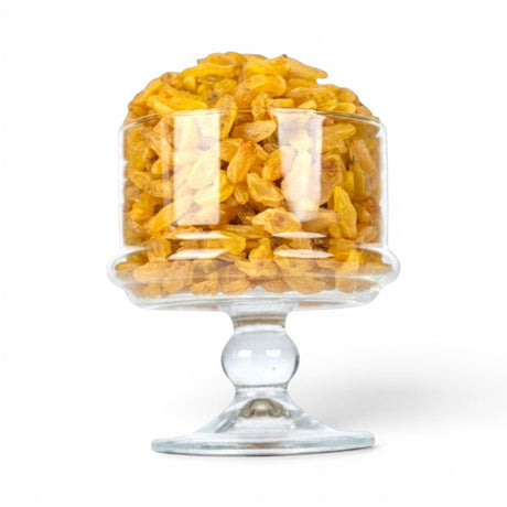 Mahnaz Food long golden raisins piled in a clear glass pedestal bowl against a white background