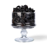 Mahnaz Food original black raisins served in a clear glass pedestal bowl against a white background