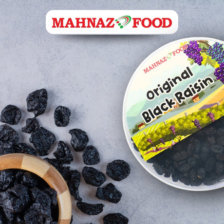 Mahnaz Food original black raisins in a clear round container with a wooden bowl of loose dried fruit on grey surface