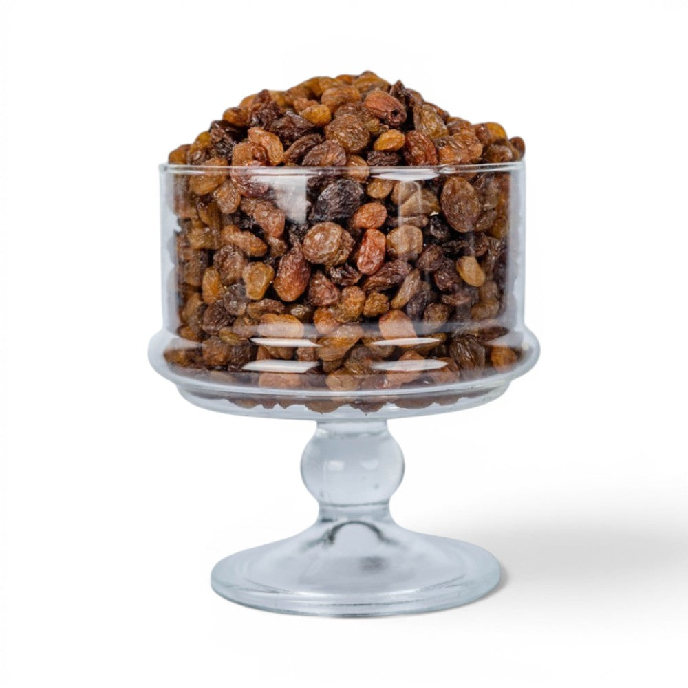 Mahnaz Food dried sultana raisins piled high in a clear glass pedestal bowl against a white background.