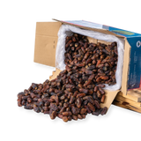 Mahnaz Food premium Mariami dates spilled from a wholesale cardboard box on a white background