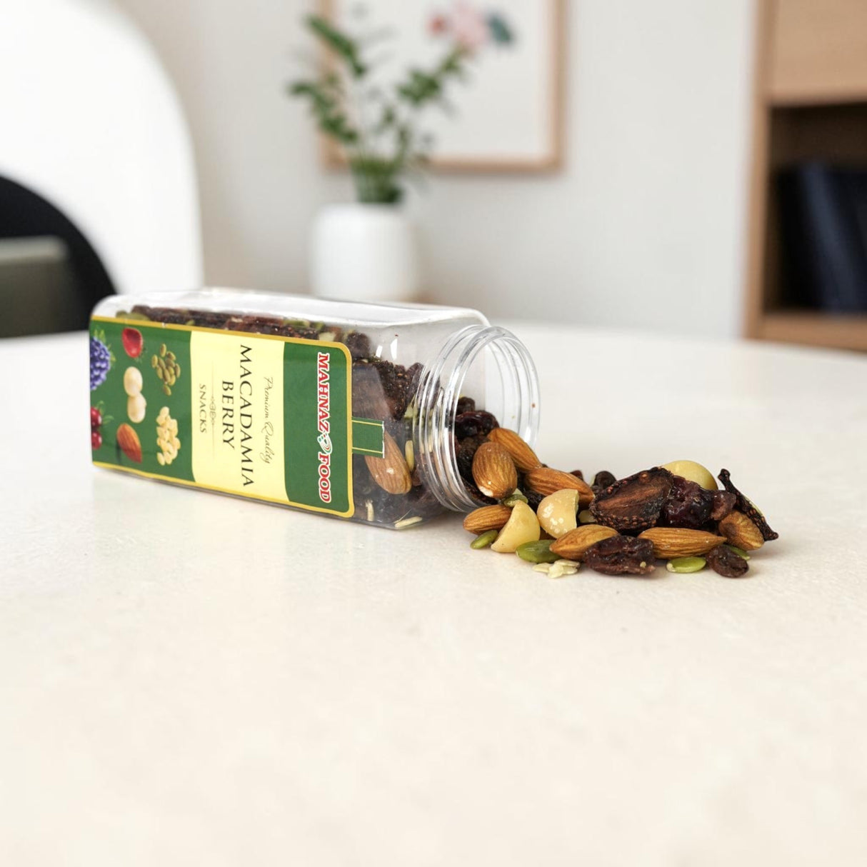 Mahnaz Food macadamia and berry nut mix spilling from a clear plastic jar onto a white table