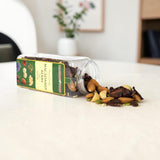 Mahnaz Food macadamia and berry nut mix spilling from a clear plastic jar onto a white table