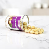 Mahnaz Food premium macadamia nuts spilled from a clear plastic jar on a white background
