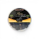 Mahnaz Food Premium Ajwa Organic Dates in a clear plastic container with a black label featuring palm trees and Arabic script.