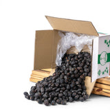Mahnaz Food premium Ajwa dates spilling from a cardboard box, dark brown, soft texture, naturally dried, rich in nutrients.
