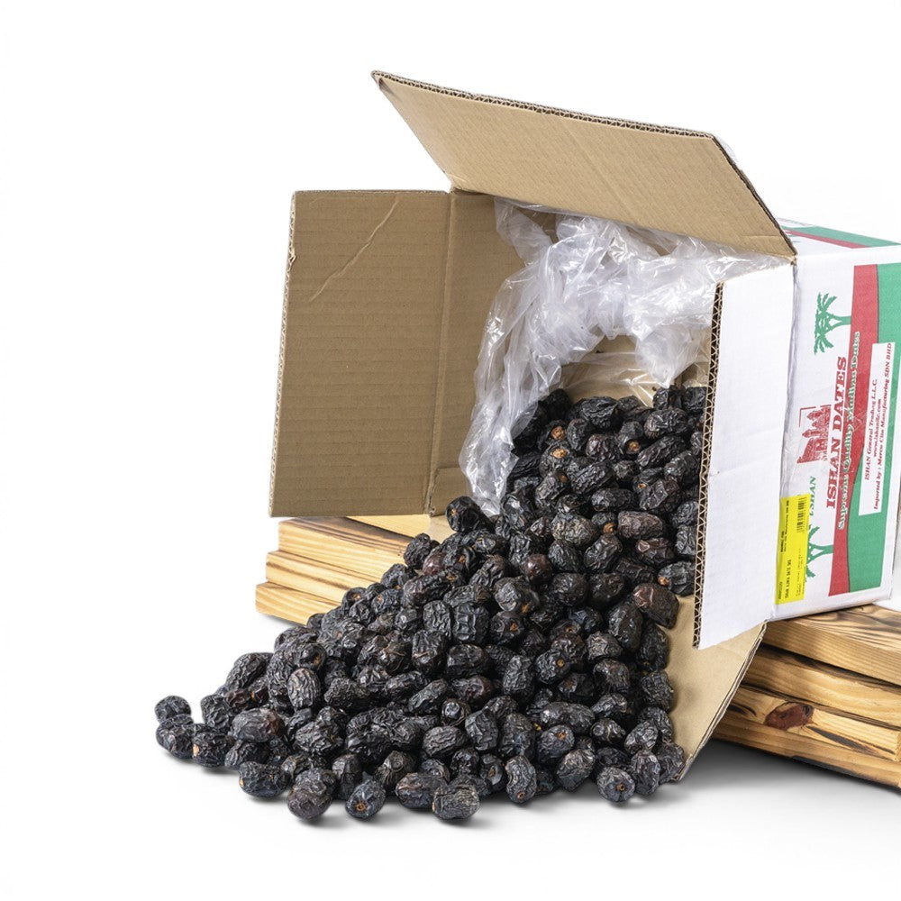 Mahnaz Food premium Ajwa dates spilling from a cardboard box. Dark brown, soft, and naturally sweet.