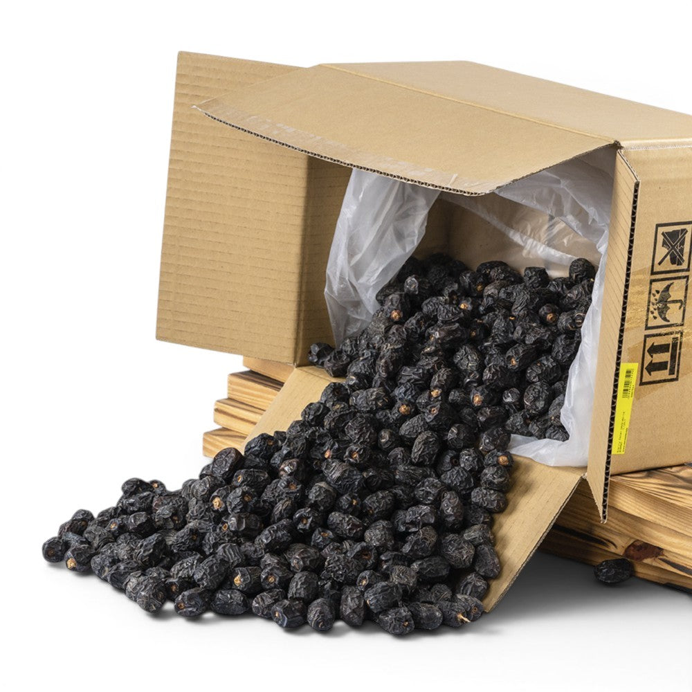 Mahnaz Food premium Ajwa dates spilling from a cardboard box, dark brown and soft texture.