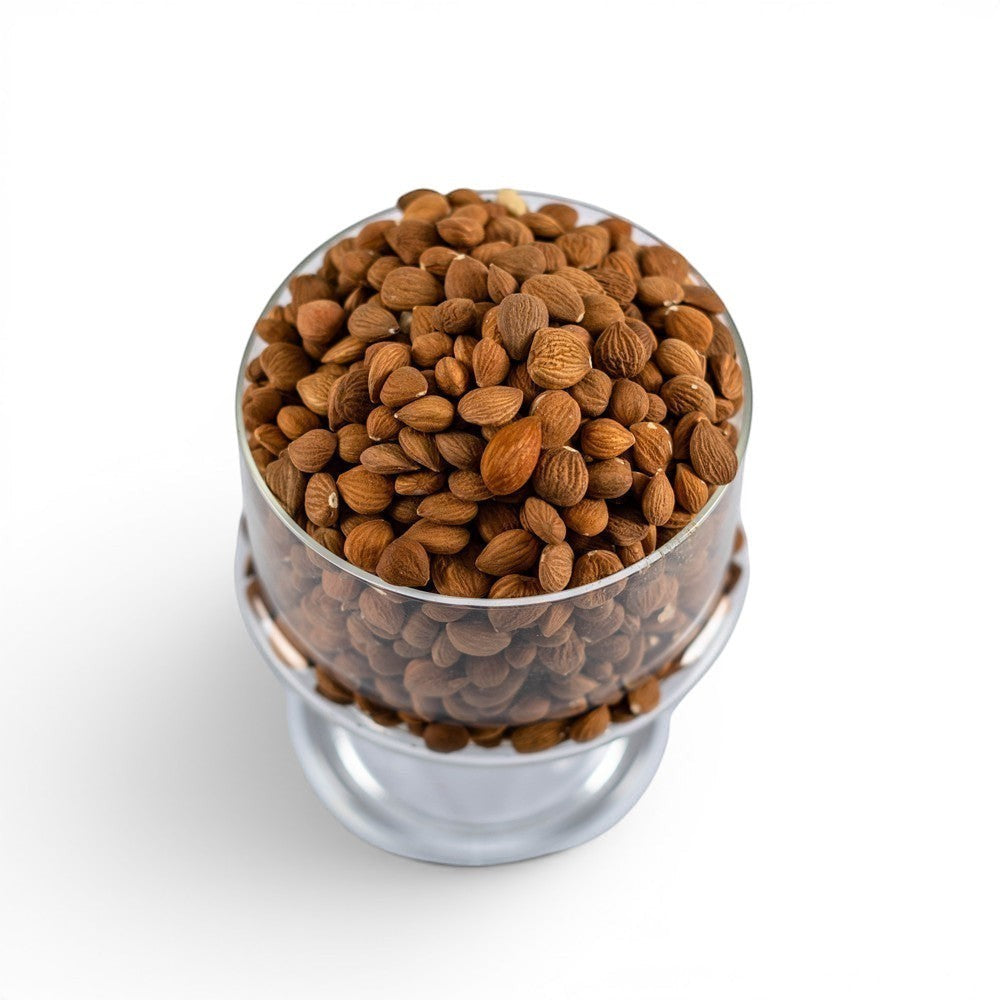 Mahnaz Food bitter apricot seeds in a clear glass bowl on a white background