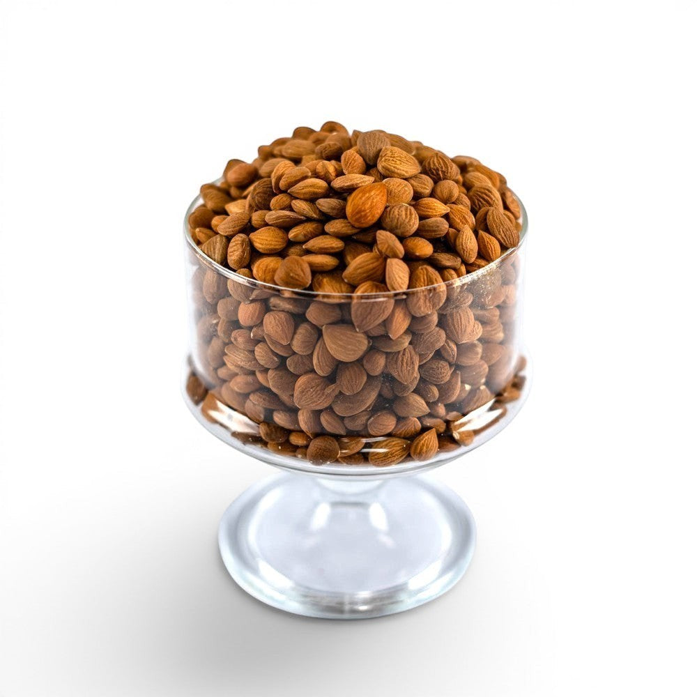Mahnaz Food bitter apricot seeds in a clear glass bowl on a white background