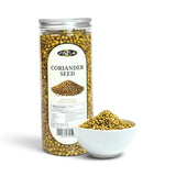 Mahnaz Food coriander seeds in a clear plastic jar next to a small white bowl filled with whole dried seeds.