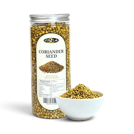 Mahnaz Food coriander seeds in a clear plastic jar next to a small white bowl filled with whole dried seeds.