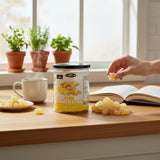 Mahnaz Food dried ginger cubes in a plastic jar with sugar coating, served on a wooden table with a hot drink.
