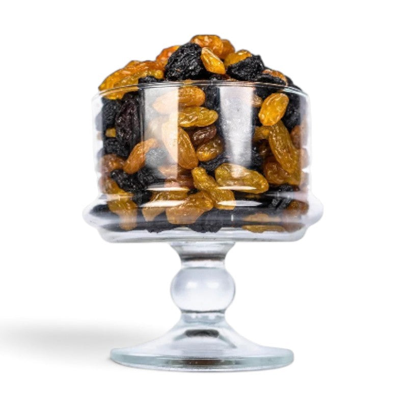 Mahnaz Food jumbo black and golden raisins served in a clear glass pedestal bowl on a white background