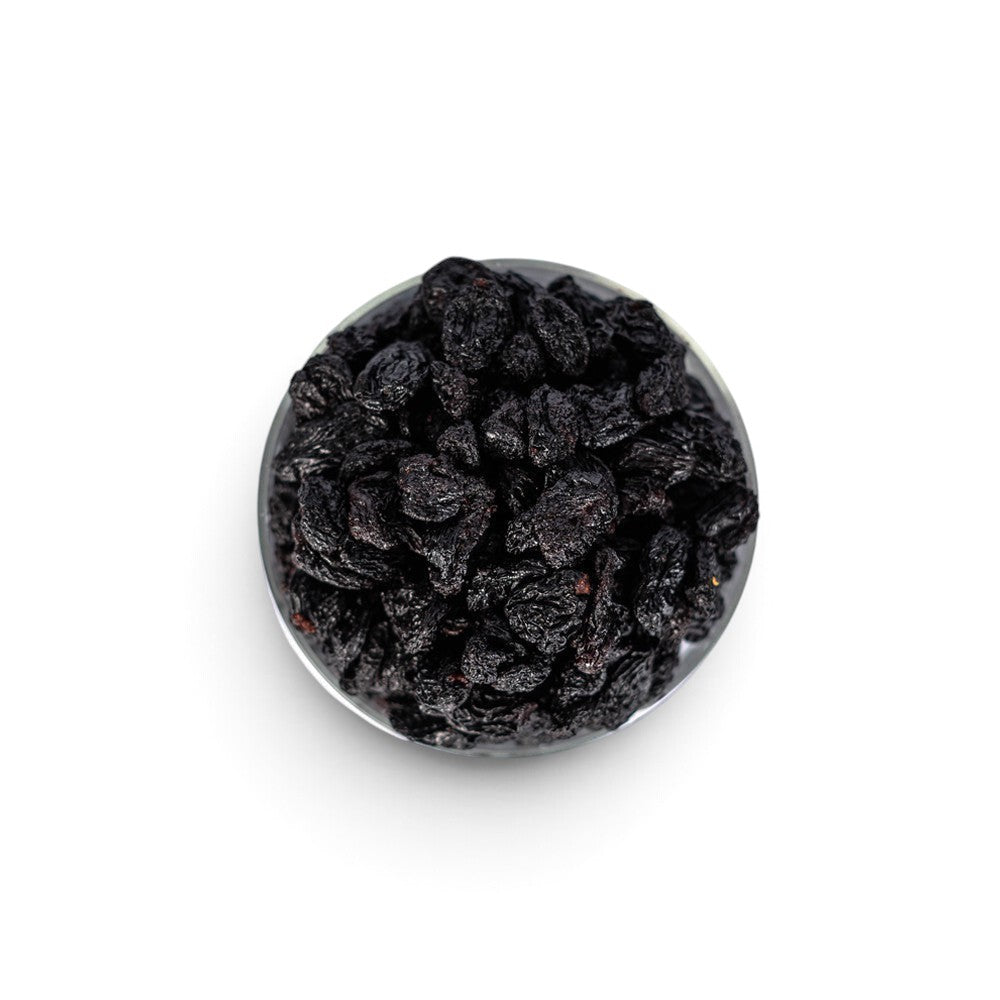Mahnaz Food jumbo black raisins in a glass bowl, a healthy dried fruit snack rich in fiber and antioxidants.