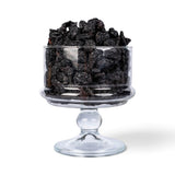 Mahnaz Food jumbo black raisins piled high in a clear glass pedestal bowl against a white background