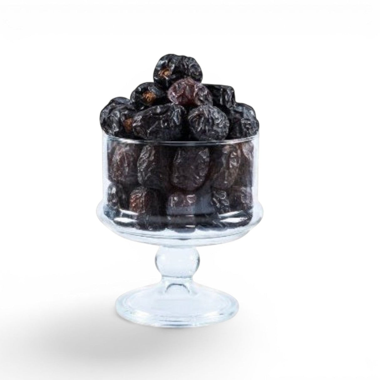 Mahnaz Food Madinah Ajwa dates in a clear glass pedestal bowl, dark brown to black with wrinkles.