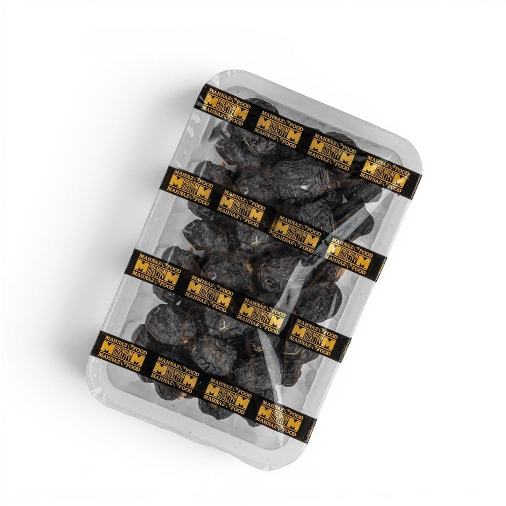 Mahnaz Food Madinah Ajwa dates, dark brown to black, wrinkled, soft dry fruit in a clear plastic tray.