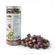 Mahnaz Food Rose Tea loose dried rose buds in a clear jar and scattered on a white surface. Herbal remedies.