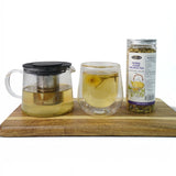 Mahnaz Food Sugar Balance herbal tea blend in a glass teapot and double-walled glass cup, with a 30g jar of loose leaf tea.